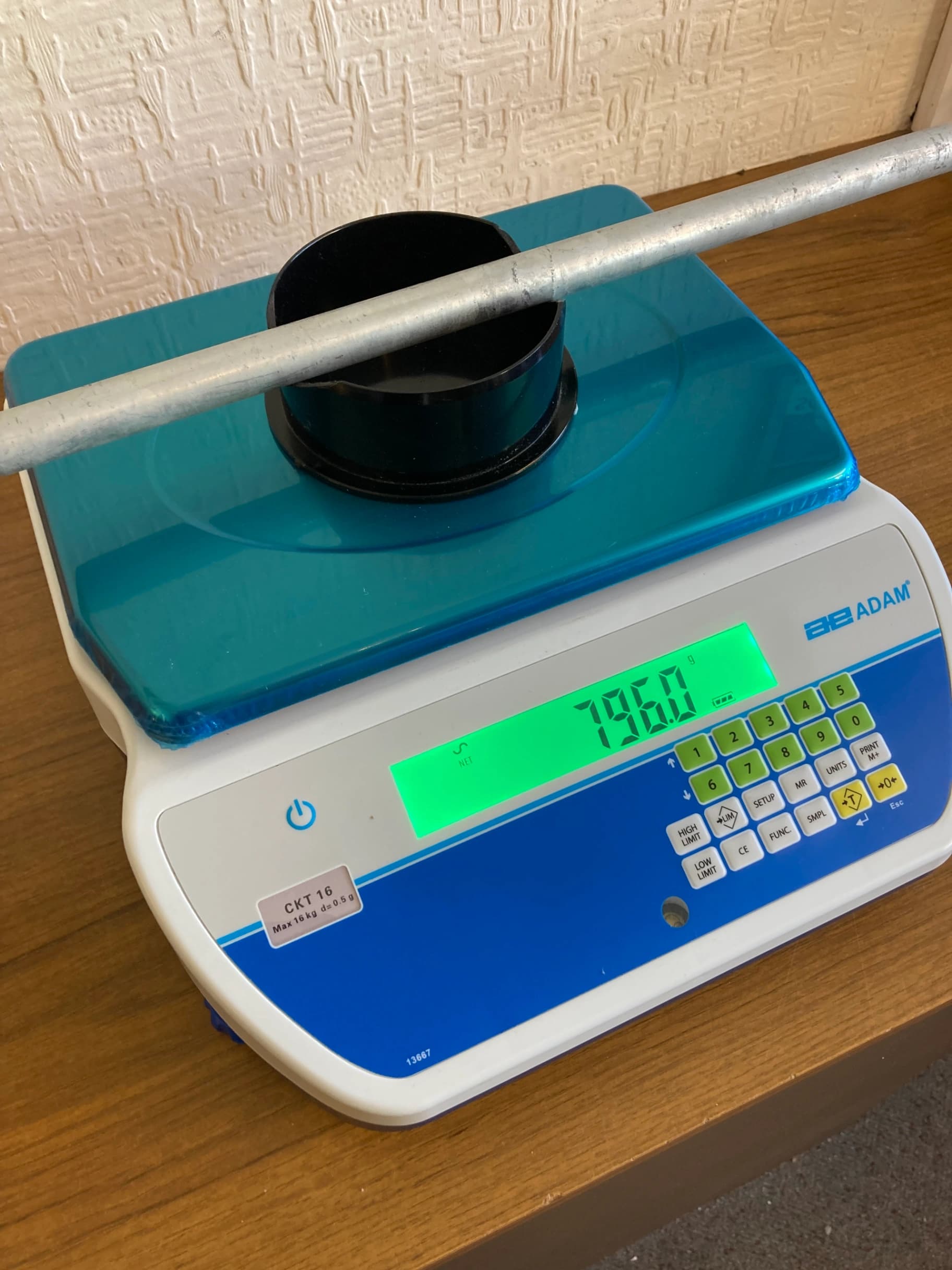 Portable athletics weighing scale with blue platform, black cup and metal rod; display reads 79.60, sticker reads CKT 16 Max 16 kg d=0.5 g.